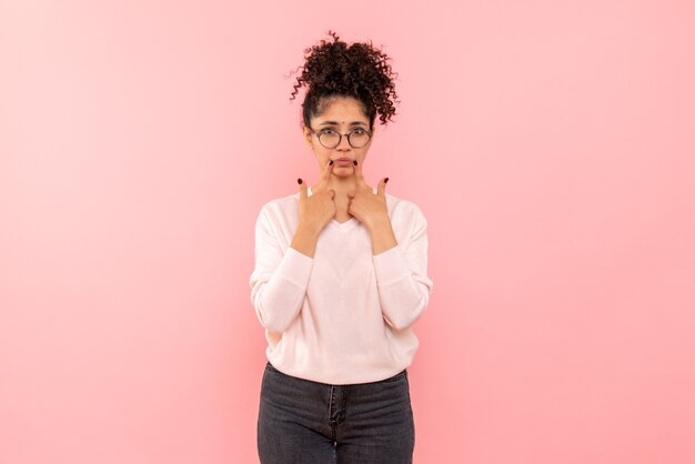 Front view of young woman with sad face on pink wall