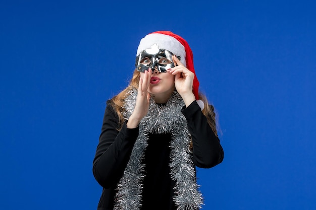 Vista frontale della giovane donna con maschera d'argento sulla parete blu