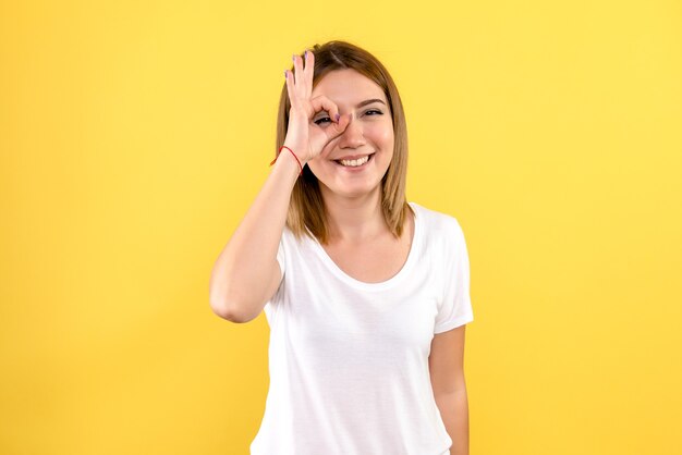 Front view of young woman with smile on yellow wall