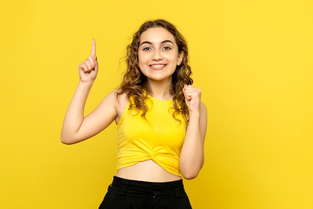 Vista frontale della giovane donna con il sorriso sulla parete gialla