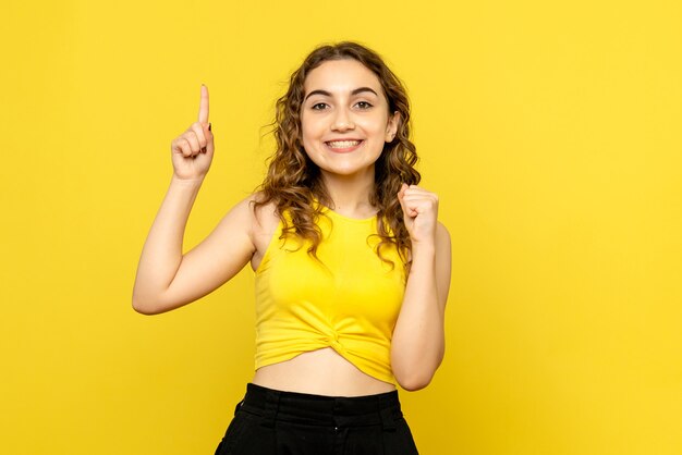 Вид спереди молодой женщины с улыбкой на желтой стене