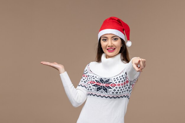 茶色の背景の休日の感情のクリスマスに笑顔の表情を持つ若い女性