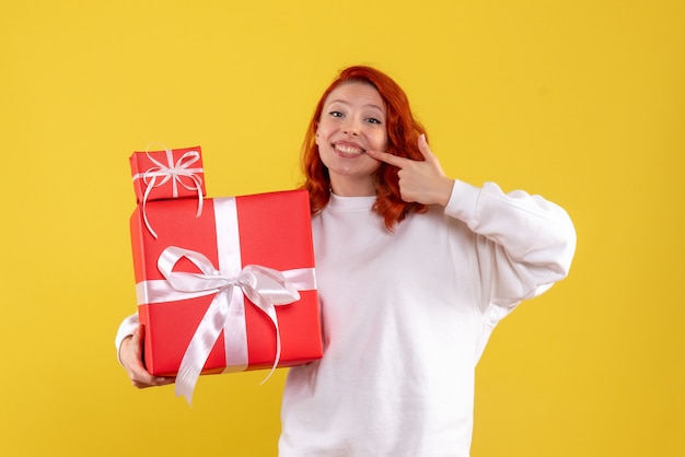 크리스마스와 젊은 여자의 전면보기 노란색 벽에 선물