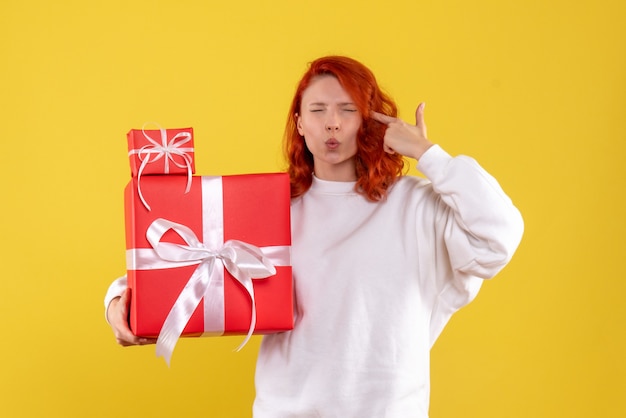 Front view of young woman with xmas presents on yellow wall