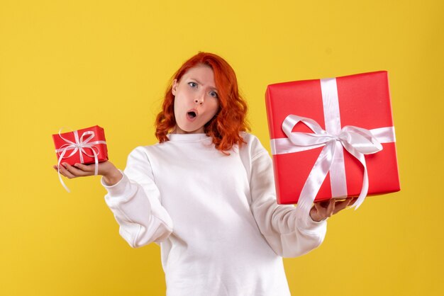 Front view of young woman with xmas presents on yellow wall