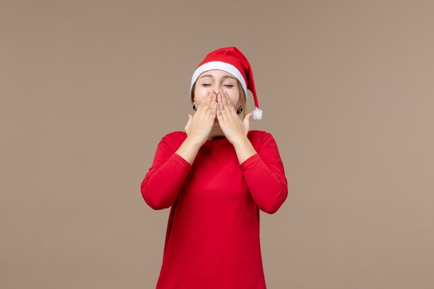 Front view of young woman yawning on brown