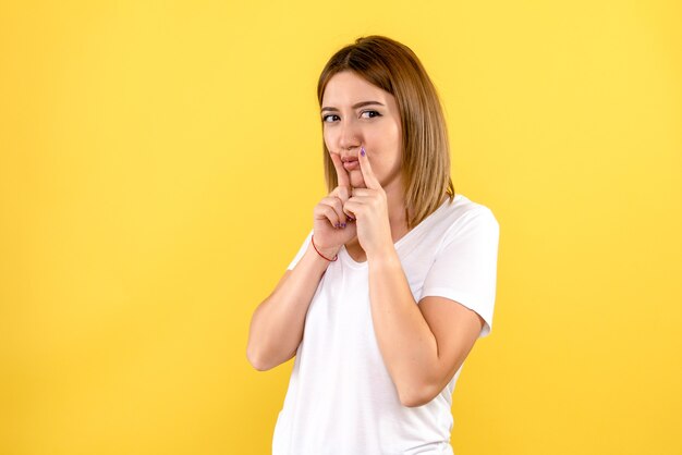 Front view of young woman on yellow wall