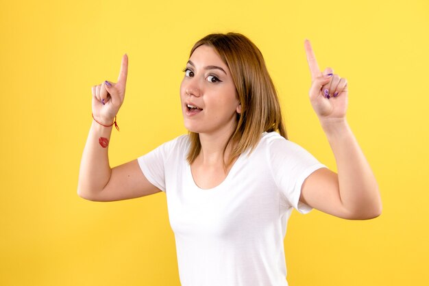 Front view of young woman on yellow wall