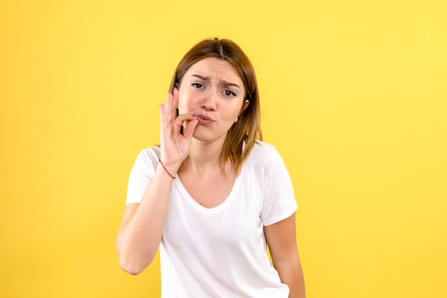 Front view of young woman on yellow wall