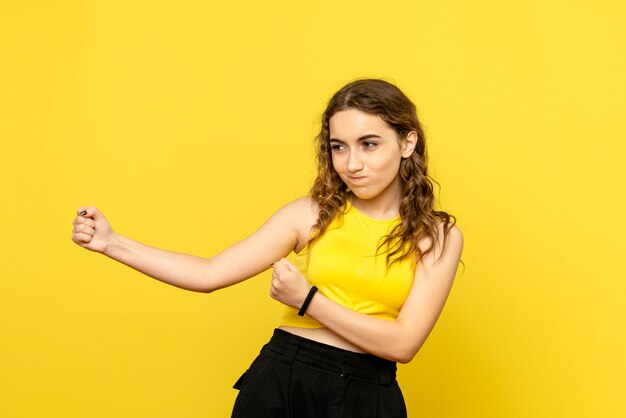 Front view of young woman on yellow wall