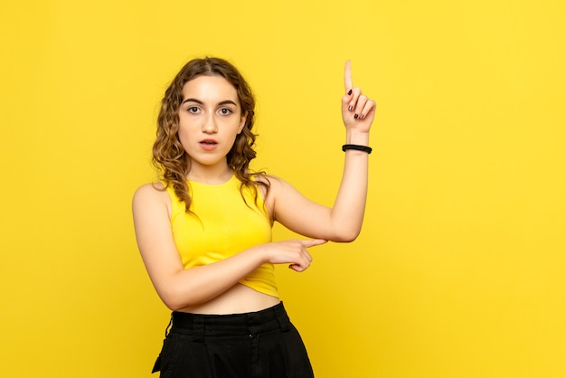 Front view of young woman on yellow wall