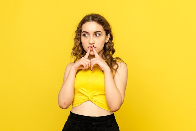 Front view of young woman on yellow wall