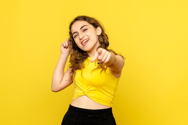 Front view of young woman on yellow wall