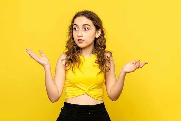 Front view of young woman on yellow wall