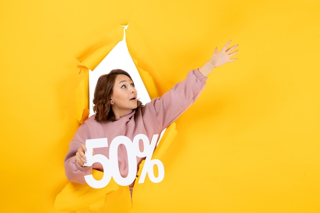 Free photo front view of young wondered lady showing fifty percentage sign and looking up on yellow torn