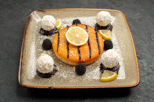 Front view yummy cake dessert with lemon slices and coconut candies on dark background pie dessert tea sweet cake candy