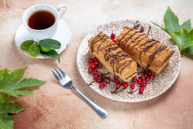 Вкусный кусок торта с чаем и ягодами на свету, вид спереди