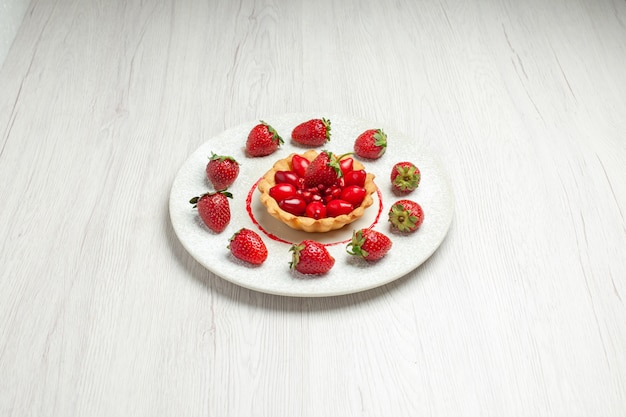 Вкусный торт со свежими фруктами внутри тарелки на белом столе, фруктовый торт, десерт, вид спереди