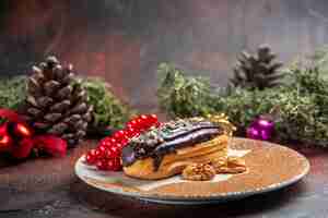 Free photo front view yummy choco eclairs with red berries on dark background