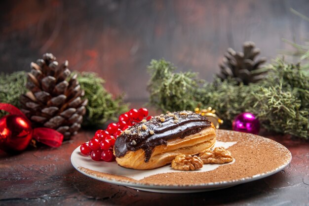 Front view yummy choco eclairs with red berries on dark background