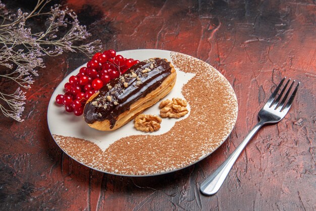 暗い床に赤いベリーと甘いチョコエクレアの正面図パイデザートケーキ甘い