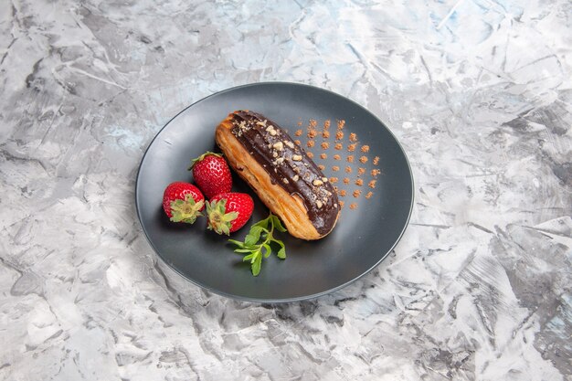 Front view yummy choco eclairs with strawberries on the light table dessert cake candy