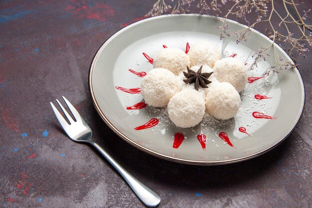 Free photo front view yummy coconut candies round formed with red icings on dark space