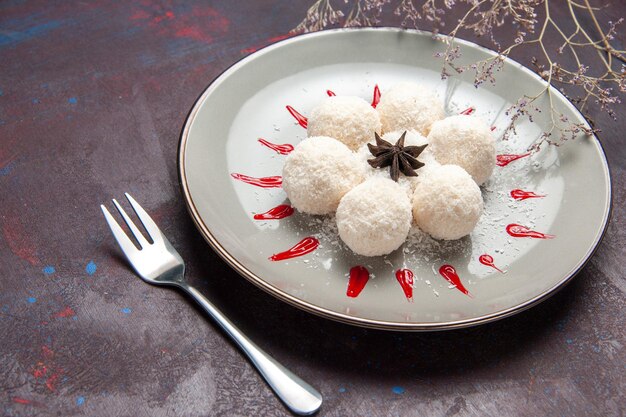 Foto gratuita vista frontale deliziose caramelle al cocco rotonde formate con glasse rosse su spazio scuro