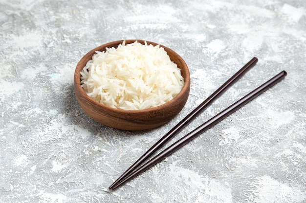 Бесплатное фото Вкусный приготовленный рис, вид спереди на коричневой тарелке на белом пространстве
