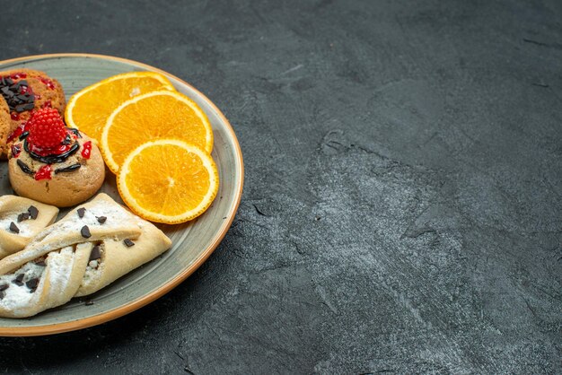 Front view yummy cookies with fruity pastries and orange slices on a dark surface fruit sweet cake pie tea sugar