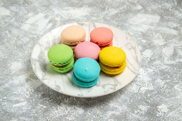 Front view yummy french macarons colorful cakes inside plate on the white surface cake sugar biscuit sweet pie cookies