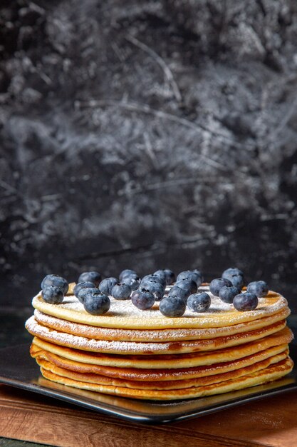 Front view yummy honey cake with blueberries inside plate dark surface