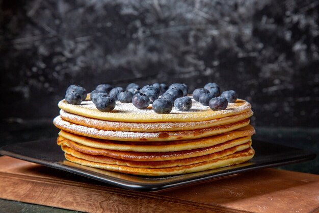 Front view yummy honey cake with blueberries inside plate dark surface