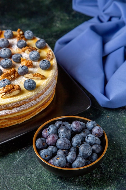 Torta di miele squisita vista frontale con mirtilli e noci all'interno della superficie scura del piatto