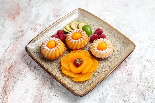 Front view yummy little cakes with sliced fruits on a white space