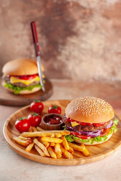 Вкусный мясной чизбургер с картофелем фри на светлой поверхности разделочной доски, вид спереди