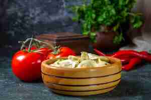 Free photo front view yummy meat dumplings inside wooden plate with fresh tomatoes on dark surface