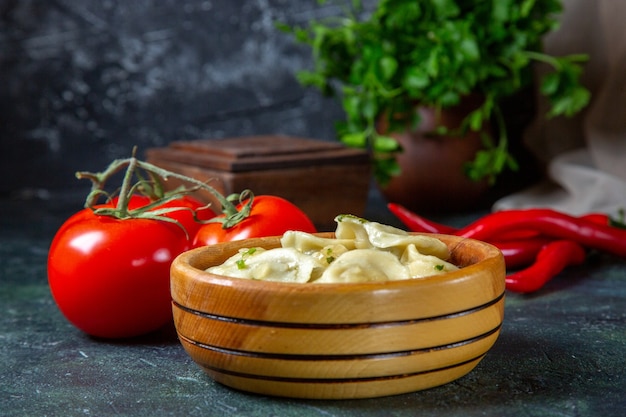 Front view yummy meat dumplings inside wooden plate with fresh tomatoes on dark surface