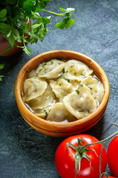 Front view yummy meat dumplings with fresh tomatoes and greens on dark surface