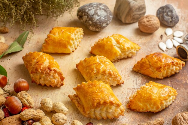 Front view yummy nut pastries with fresh nuts on brown desk pastry pie sweet cake nut