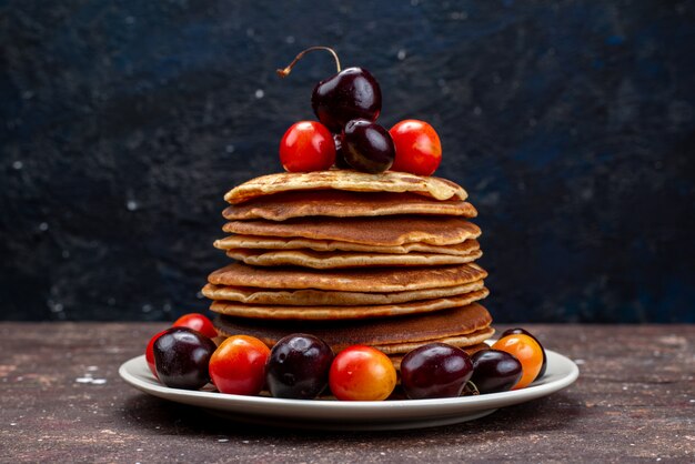 A front view yummy pancakes with cherries inside white plate on the dark desk fruit pancake