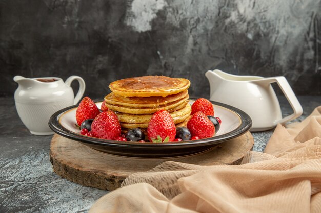 Front view yummy pancakes with fruits and honey on light surface sweet fruit milk