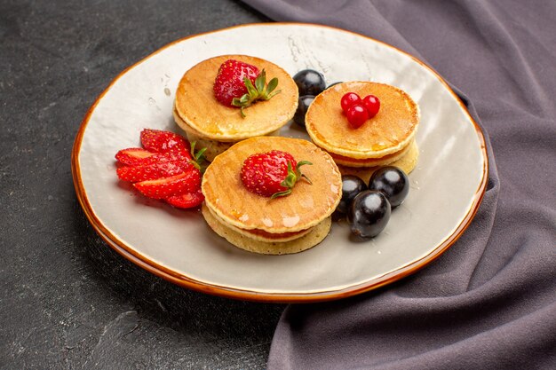 Вкусные блины с оливками и фруктами на темной поверхности фруктовый сладкий торт, вид спереди