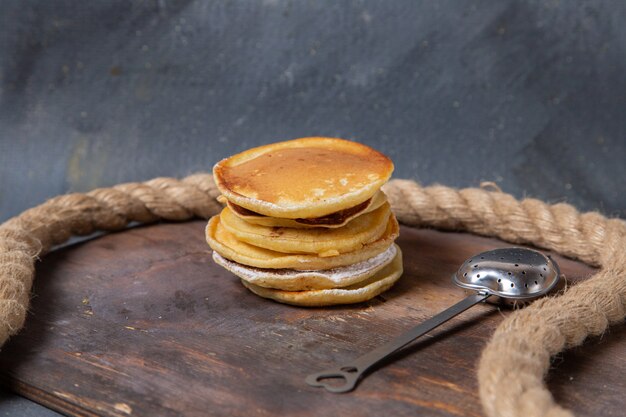 Front view yummy pancakes with ropes on the wooden background sweet sugar food meal breakfast