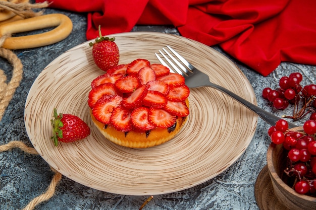 Vista frontale della gustosa torta di fragole con frutti di bosco sulla superficie scura