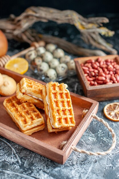 밝은 회색 표면에 작은 케이크와 견과류가 있는 맛있는 달콤한 비스킷 전면 보기