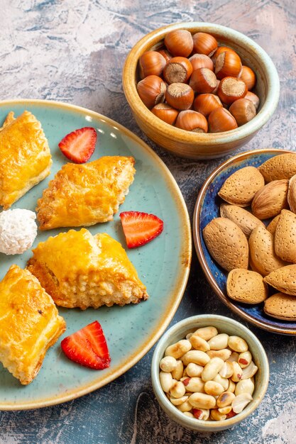 Front view of yummy sweet cakes with nuts on blue surface