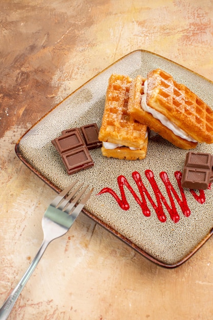 Vista frontale deliziose torte di waffle con barrette di cioccolato sullo sfondo marrone