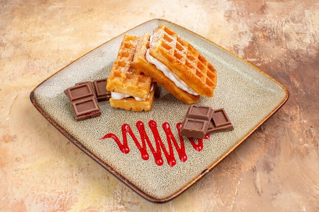 Front view yummy waffle cakes with chocolate bars on brown background