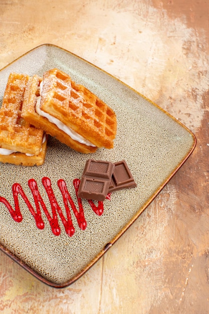 Вкусные вафельные торты с шоколадными батончиками на коричневом фоне, вид спереди